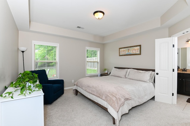 bedroom with light colored carpet, a tray ceiling, visible vents, and multiple windows