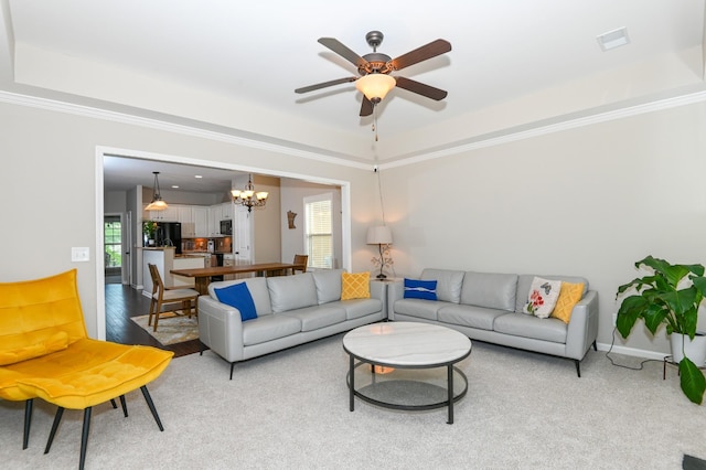 living room featuring crown molding, a healthy amount of sunlight, a raised ceiling, and ceiling fan with notable chandelier