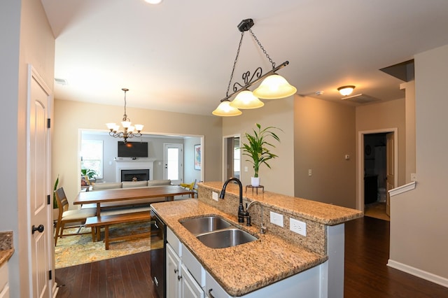 kitchen with a sink, a fireplace, black dishwasher, decorative light fixtures, and dark wood-type flooring