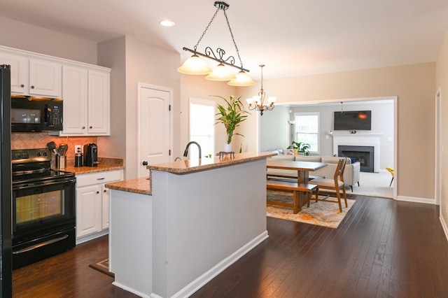 kitchen featuring light stone counters, white cabinetry, tasteful backsplash, dark wood-style floors, and black appliances