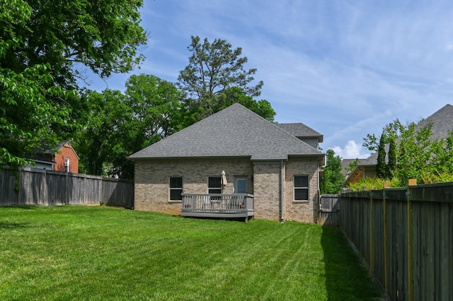 back of house with a yard, brick siding, a fenced backyard, and a deck