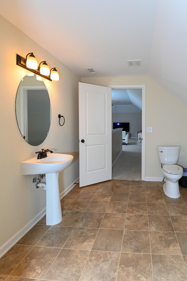 bathroom featuring toilet, baseboards, visible vents, and vaulted ceiling
