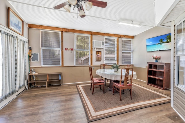 dining room featuring ceiling fan, a wall unit AC, and wood finished floors