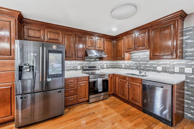 kitchen with a sink, appliances with stainless steel finishes, under cabinet range hood, and light countertops