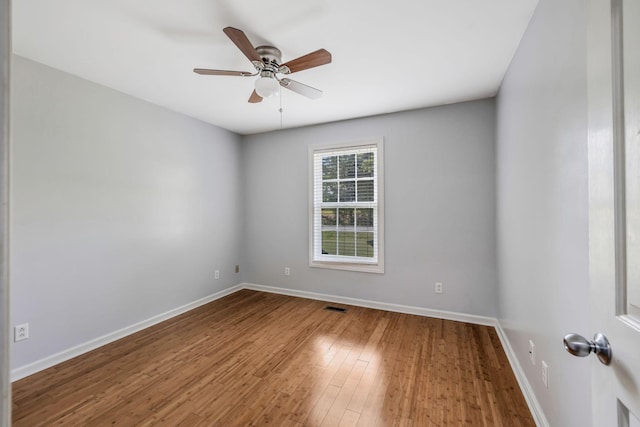 empty room featuring baseboards, ceiling fan, wood finished floors, and visible vents