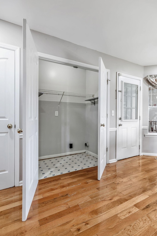 washroom featuring laundry area, baseboards, and light wood finished floors