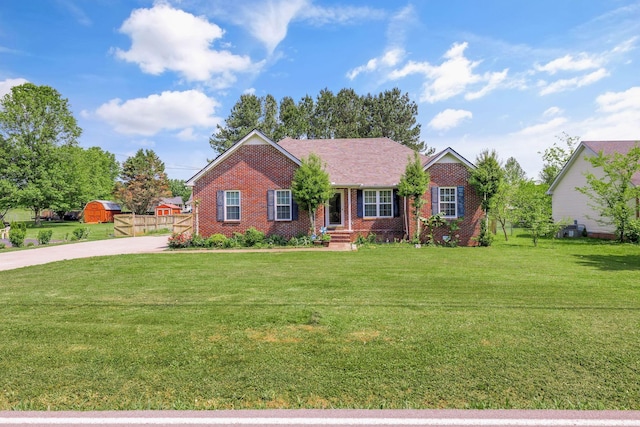 single story home featuring brick siding, fence, driveway, and a front lawn