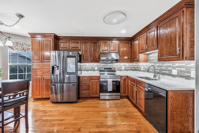 kitchen with a sink, light wood finished floors, appliances with stainless steel finishes, and light countertops
