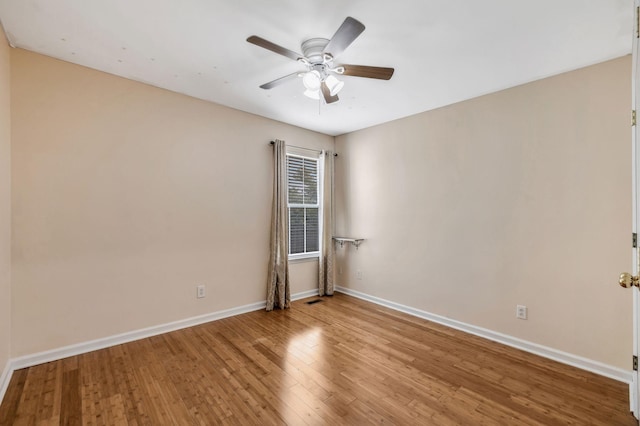 empty room with baseboards, ceiling fan, visible vents, and wood finished floors