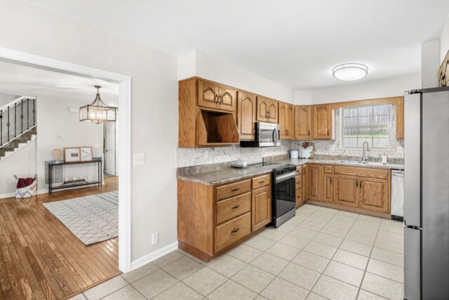 174 Hickory Ln, Jacksboro, TN 37757 - kitchen featuring decorative backsplash, brown cabinetry, stainless steel appliances, a sink, and baseboards