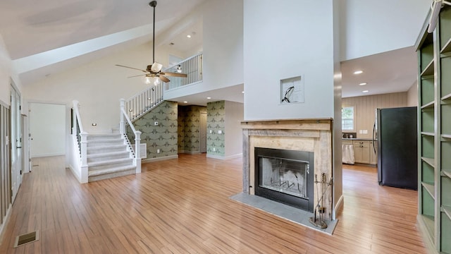1344 French Brantley Rd, Wartrace, TN 37183 - unfurnished living room with high vaulted ceiling, a fireplace with flush hearth, light wood finished floors, stairs, and ceiling fan
