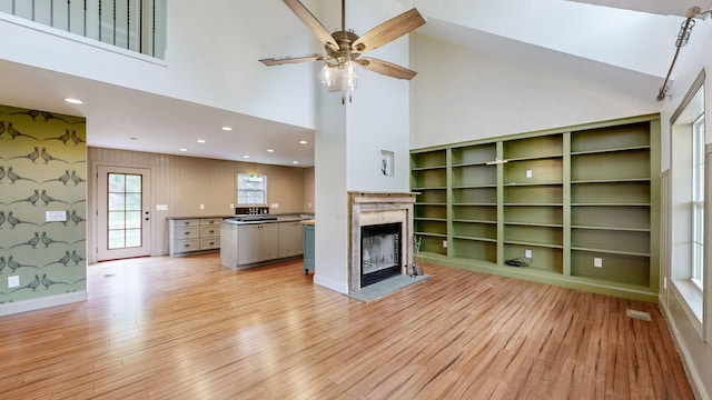 1344 French Brantley Rd, Wartrace, TN 37183 - unfurnished living room with light wood-type flooring, ceiling fan, a towering ceiling, a premium fireplace, and wallpapered walls