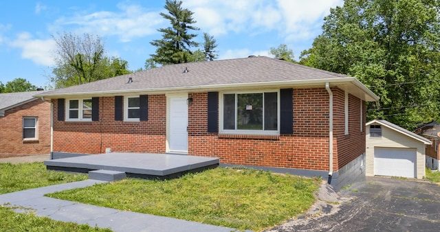 ranch-style house with aphalt driveway, a garage, brick siding, a front yard, and an outbuilding