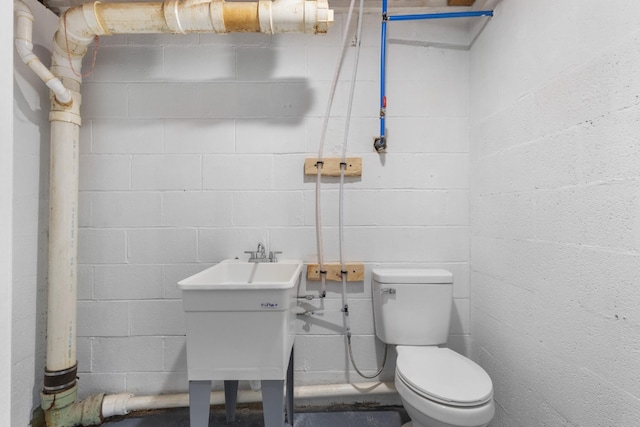 half bathroom with concrete block wall and toilet