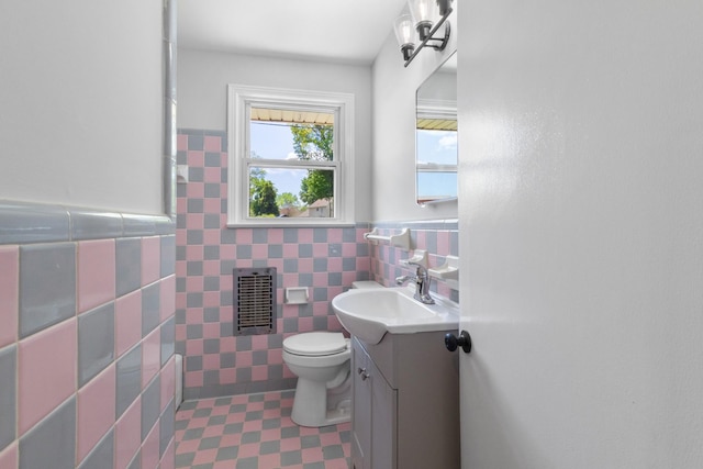 bathroom with visible vents, tile walls, wainscoting, vanity, and toilet