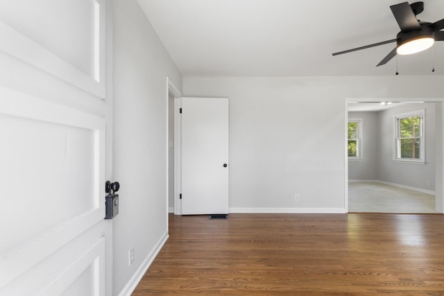 empty room with baseboards, ceiling fan, wood finished floors, and visible vents