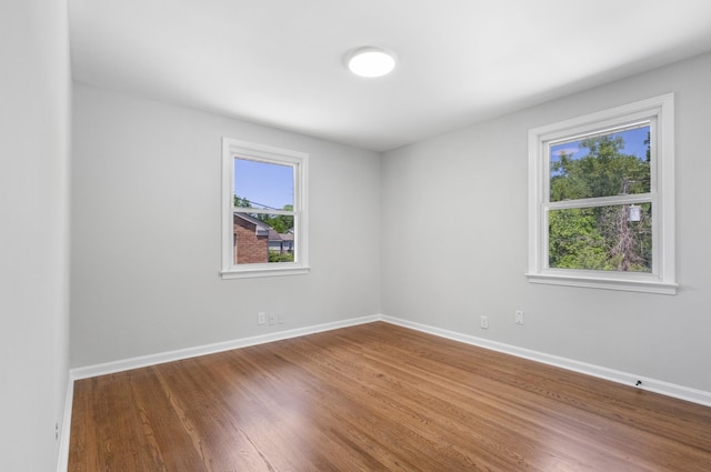 spare room with baseboards and wood finished floors