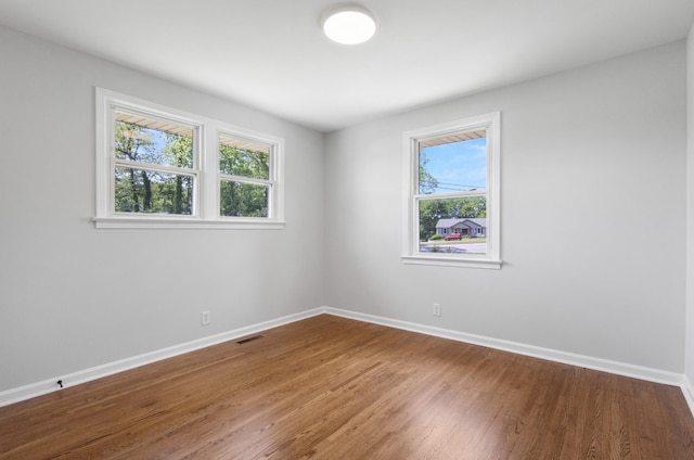 unfurnished room featuring baseboards, wood finished floors, and visible vents
