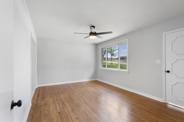empty room with baseboards, ceiling fan, and wood finished floors