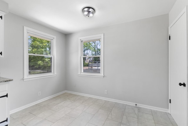 unfurnished dining area with baseboards, plenty of natural light, and marble finish floor