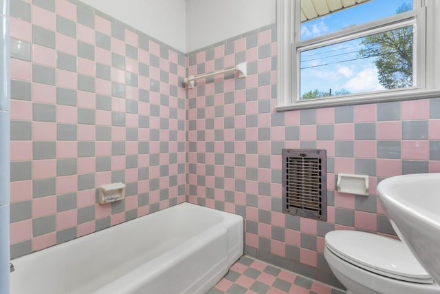 full bathroom with a sink, a bathing tub, toilet, and tile walls