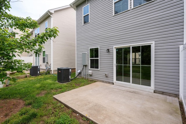 rear view of house featuring a lawn, cooling unit, and a patio area