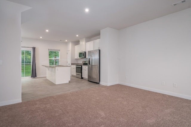 kitchen featuring white cabinetry, visible vents, stainless steel appliances, and light carpet