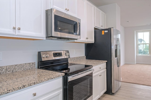 kitchen featuring light stone counters, stainless steel appliances, white cabinets, light wood finished floors, and baseboards