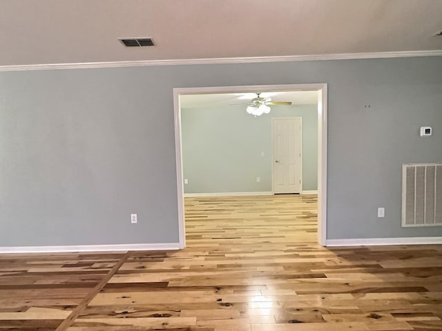 unfurnished room featuring crown molding, visible vents, wood finished floors, and baseboards