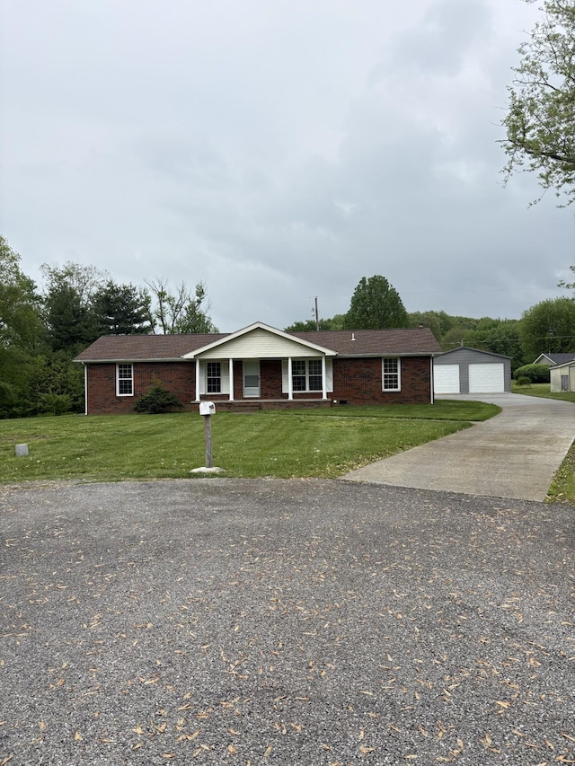 ranch-style home featuring an outdoor structure, concrete driveway, a front yard, brick siding, and a garage