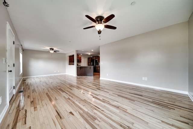 unfurnished living room featuring a ceiling fan, baseboards, and light wood-type flooring