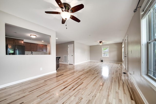 unfurnished living room featuring light wood-style floors, baseboards, ceiling fan, and visible vents