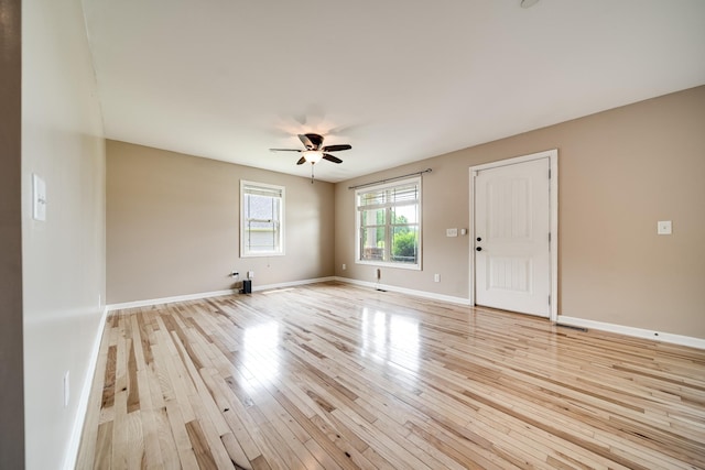 spare room featuring baseboards, a ceiling fan, light wood finished floors, and visible vents