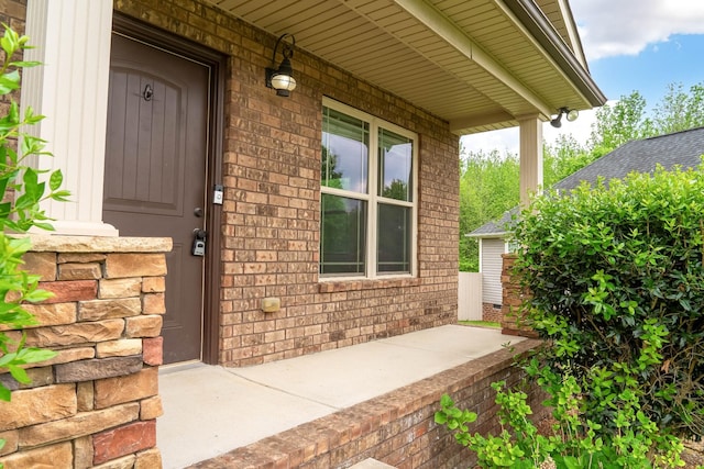 entrance to property with a porch and brick siding