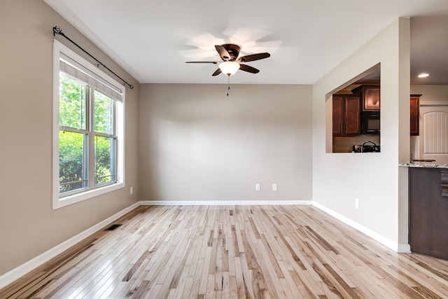 empty room featuring baseboards, a ceiling fan, light wood-style flooring, and visible vents