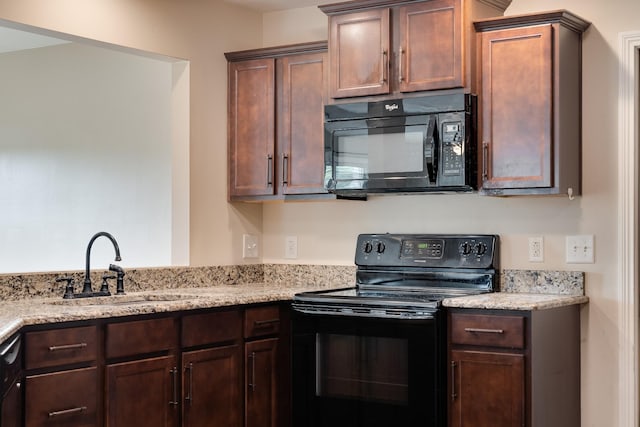 kitchen featuring a sink, dark brown cabinets, black appliances, and light stone countertops