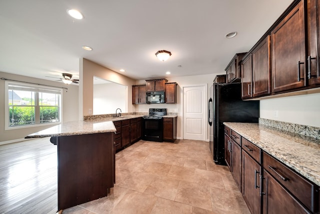 kitchen with dark brown cabinetry, a ceiling fan, a sink, light stone counters, and black appliances
