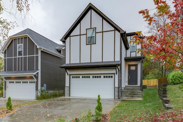 english style home with driveway, fence, board and batten siding, and an attached garage