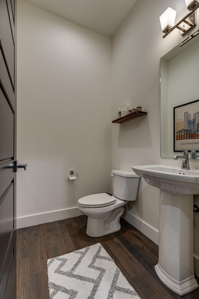 bathroom with baseboards, wood finished floors, and toilet