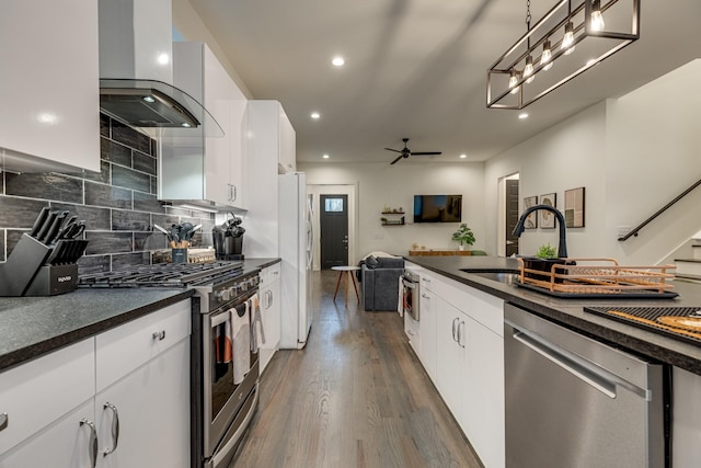 kitchen featuring wall chimney exhaust hood, open floor plan, dark countertops, and stainless steel appliances