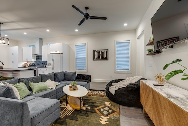 living area featuring recessed lighting, ceiling fan with notable chandelier, baseboards, and dark wood finished floors
