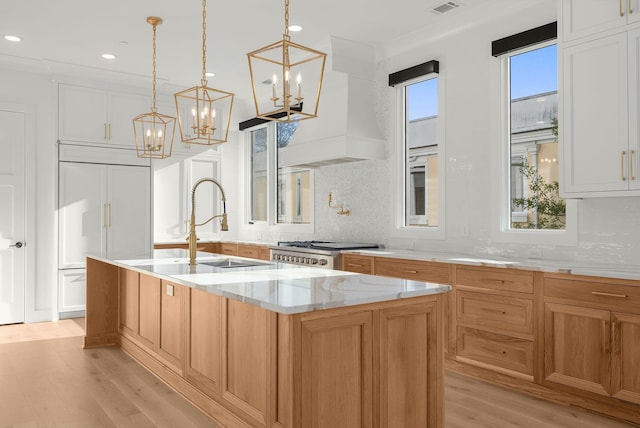 95 Leonard Ave Unit 1, Nashville, TN 37205 - kitchen featuring a chandelier, light wood-type flooring, a kitchen island with sink, a sink, and light stone counters
