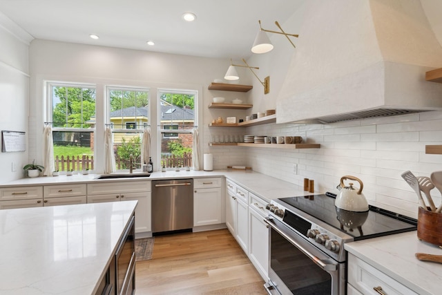 kitchen with stainless steel appliances, custom exhaust hood, a sink, and plenty of natural light