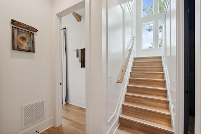 stairway featuring baseboards, visible vents, and wood finished floors