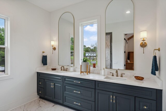 full bathroom featuring a sink, baseboards, double vanity, and marble finish floor