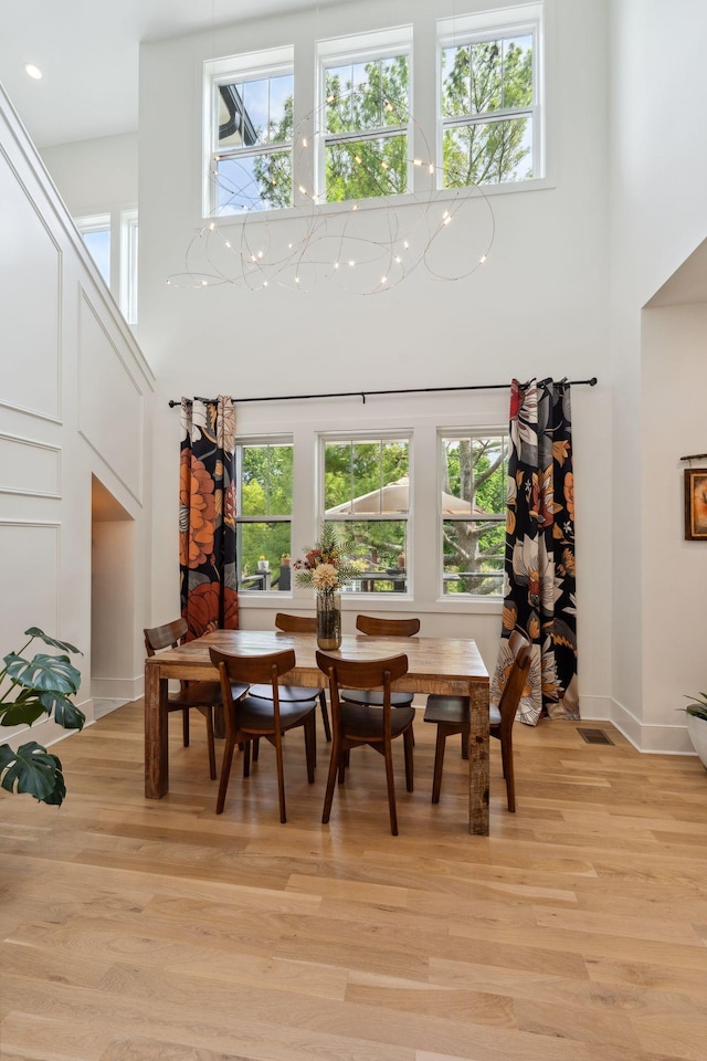 dining room with visible vents, a towering ceiling, light wood-type flooring, baseboards, and recessed lighting