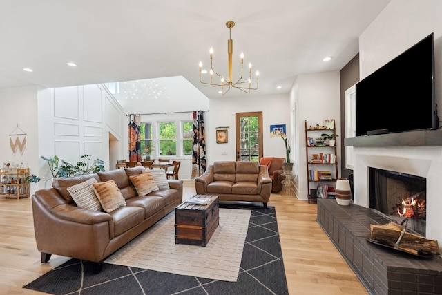 living area featuring a lit fireplace, an inviting chandelier, recessed lighting, and light wood finished floors
