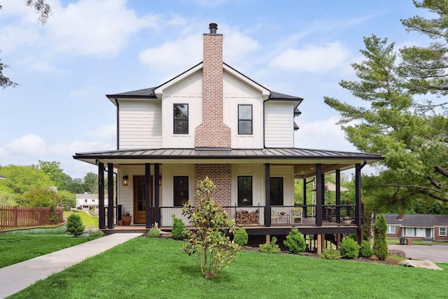 country-style home featuring covered porch, a standing seam roof, and a chimney