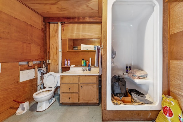 bathroom featuring toilet, wood walls, and vanity