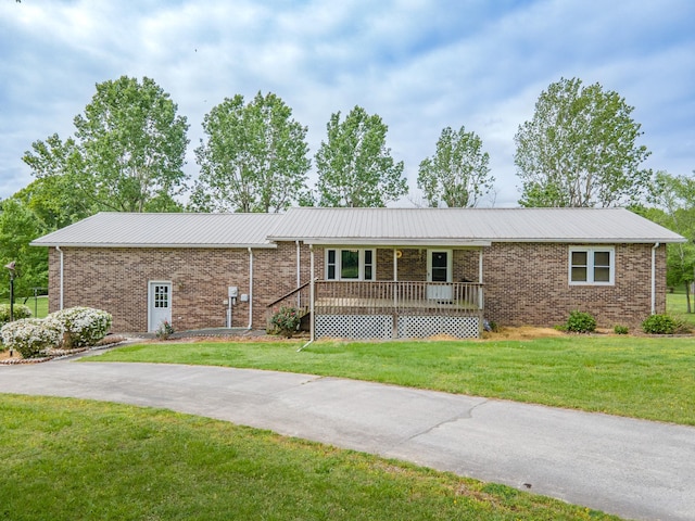 ranch-style house featuring metal roof, a front lawn, and brick siding